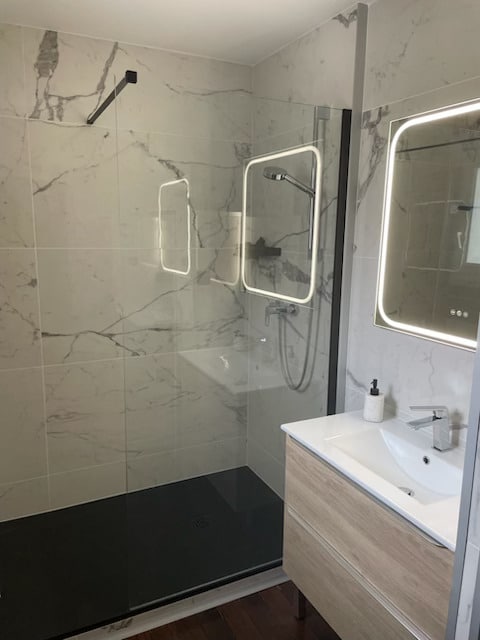 Douche à l'italienne en marbre, receveur noir et meuble vasque bois avec miroir LED.