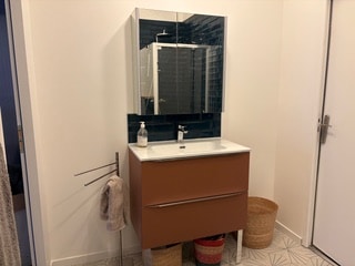Meuble vasque terracotta moderne avec miroir armoire, dosseret bleu et paniers en osier dans une salle de bain épurée.